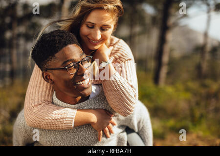 L uomo dando piggyback ride a hiss ragazza all'esterno. Coppia romantica che si diverte all'esterno. Foto Stock