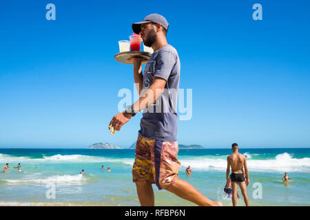 RIO DE JANEIRO - Marzo 2018: una spiaggia senza licenza di vendita del fornitore in casa caipirinha cocktail guarda per i potenziali clienti della spiaggia di Ipanema. Foto Stock