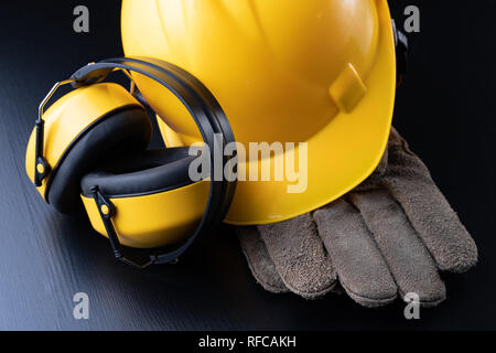 Casco e accessori per lavoratori edili. Gli accessori necessari per il lavoro in cantiere. Sfondo scuro. Foto Stock