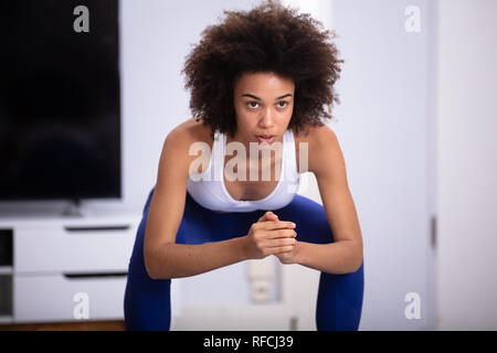 Giovane donna in usura Fitness facendo esercizio di Squat a casa Foto Stock