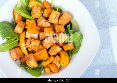 Il tofu in agrodolce con peperoni su letto di spinaci Foto Stock