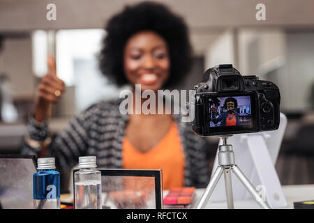 Piuttosto americano africano donna con capelli ricci facendo un contenuto video per beauty blog Foto Stock