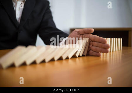 Imprenditore si ferma mano domino capovolta continua nel senso che ostacolavano il fallimento aziendale. Stop Over questo fallimento aziendale concetto. Foto Stock