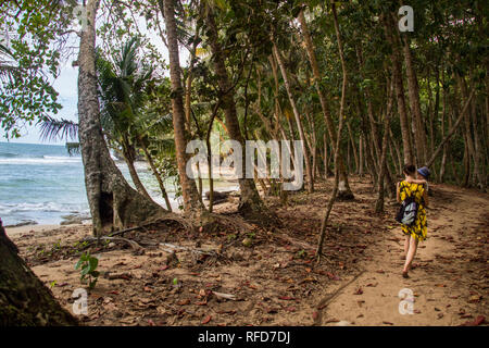 Una foto di una donna e il figlio a piedi su un sentiero vicino ad una bellissima spiaggia con acque blu turchese a Manzanillo National Park, Costa Rica Foto Stock