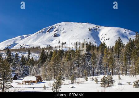 Piccole cabine alla base delle montagne coperte di neve Foto Stock