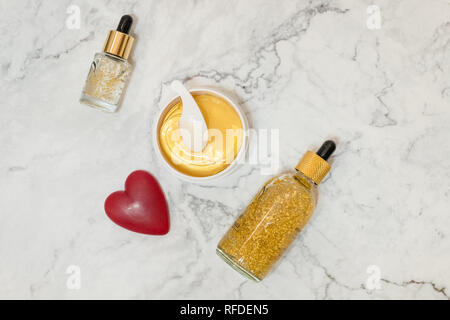 Spa prodotti cosmetici su marmo bianco lo sfondo da sopra. Bellezza blogger concetto. Copyspace.bellezza prodotti Skincare. olio, panna, siero, idrogel golden Foto Stock