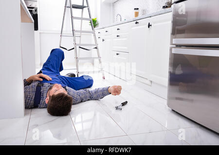 Close-up di inconscio tuttofare sdraiato sul pavimento in cucina Foto Stock