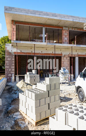 I blocchi di calcestruzzo impilate su pallet all'aperto nella parte anteriore di una casa unifamiliare in costruzione nei sobborghi di Parigi, Francia. Foto Stock