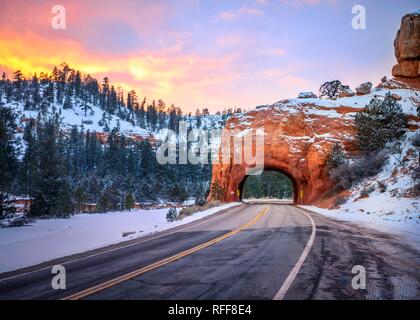 Strada con tunnel attraverso il Red Rock arco nella neve, al tramonto, Highway 12, rocce di arenaria, Rosso Canyon, Panguitch, Utah, Stati Uniti d'America Foto Stock