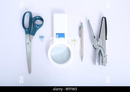 Foto di penna,cucitrice,forbice,graffetta e lente di ingrandimento. Isolato su uno sfondo bianco. Foto Stock