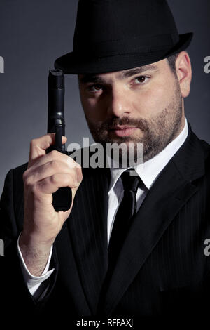 Uomo pericoloso in tuta con una pistola Foto Stock