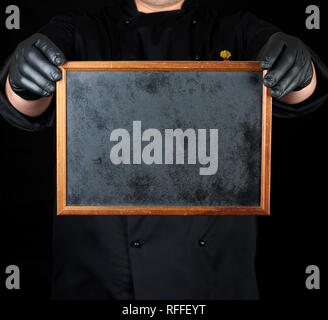Chef in nero uniforme e nero Guanti in lattice mantiene un vuoto di telaio in legno,spazio copia Foto Stock