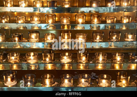 Molte candele schierate nel Santo Rosario nella cattedrale di Vancouver, Canada, splendente d'oro davanti a uno sfondo color argento Foto Stock