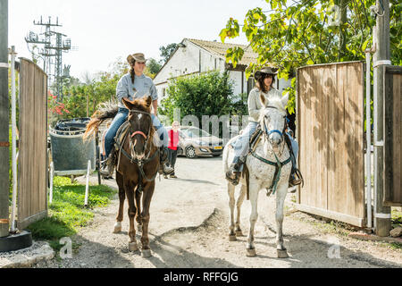 Due ragazze a cavallo in attesa dell'arrivo dei pensionati dalla città Foto Stock