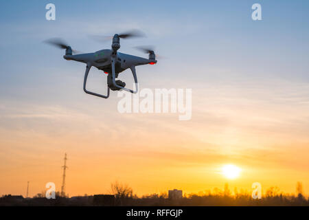 Chiusura del drone volare in aria al tramonto con il cielo giallo in background. Foto Stock