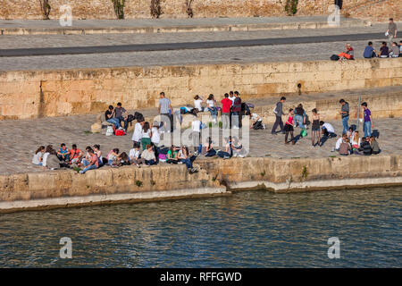 Un gruppo di giovani studenti, appendere fuori sul fiume waterfront nella città di Siviglia in Andalusia, Spagna Foto Stock