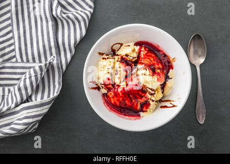 Delizioso gelato alla vaniglia con salsa di lamponi e choco strisce Foto Stock