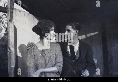 Circa trenta, Storico, romantico giovane adulto giovane indossando i vestiti dei era seduto in una vecchia capanna insieme all'esterno guardando ogni altro, Inghilterra, Regno Unito. Foto Stock