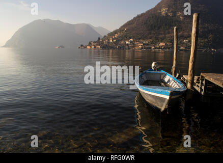 Piccola barca parcheggiata vicino ad un molo in legno sul lago d'Iseo nel Nord Italia, vista sul Monte Isola isola. Foto Stock