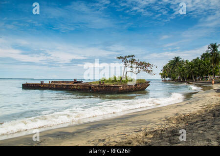 Un paesaggio colorato foto di un vecchio arrugginito nave affondata relitto ricoperto di vegetazione presso la spiaggia di Puerto Viejo, Limon Costa Rica. Foto Stock