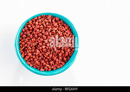 Annatto semi in vaso blu, isolato su sfondo bianco, vista dall'alto Foto Stock