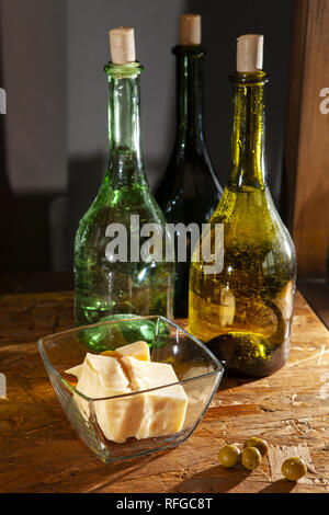 three bottles of olive oil and parmesan cheese on a wooden surface Foto Stock