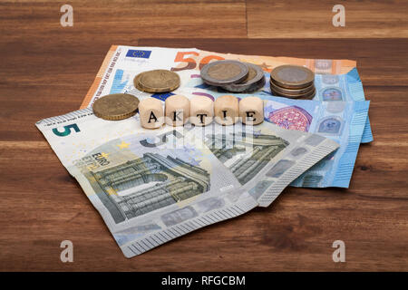 Die Euro Geldscheine und Münzen liegen auf dem Tisch mit dem Wort Aktie Foto Stock