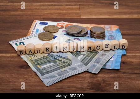 Die Euro Geldscheine und Münzen liegen auf dem Tisch mit dem Wort Baukindergeld Foto Stock