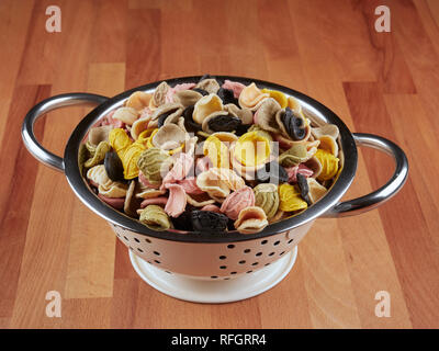 Colorato non cotti orecchiette in un piccolo scolapasta Foto Stock