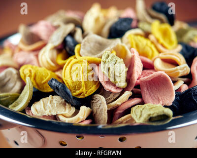 Colorato non cotti orecchiette in un piccolo scolapasta, vista da vicino Foto Stock