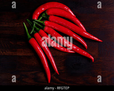 Red chilis al buio su un rustico in legno di rovere board Foto Stock