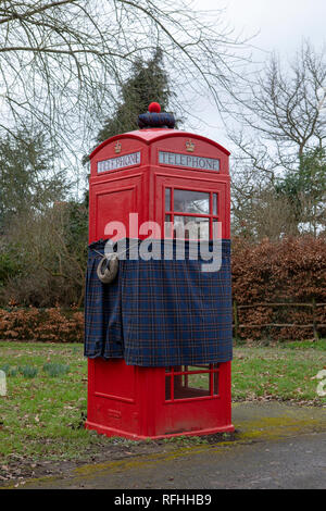 Telefono rosso box ottiene il Robbie Burns makeover. Sporting un kilt, sporran e hat guardando meglio di più dopo un pesante di notte. Foto Stock