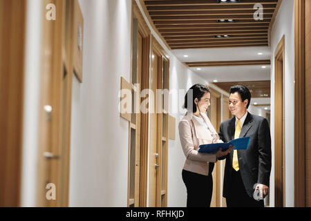 Imprenditrice spiegando di documenti a Felice Client cinesi in Bank office Foto Stock