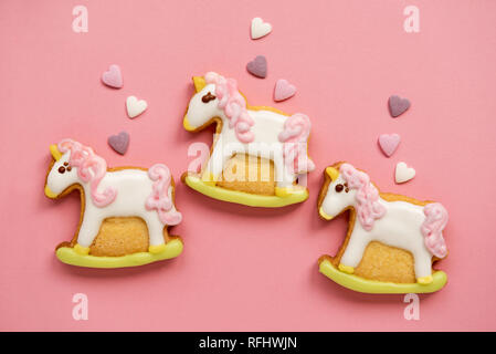 Unicorn zucchero a forma di cookie decorate con tonalità di glassa reale su sfondo rosa. Favole concetto. Vista dall'alto. Foto Stock