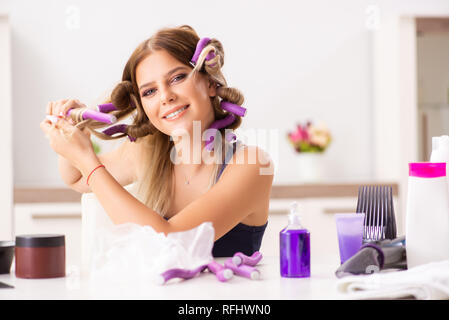 Giovane donna con arricciacapelli in Barberia Foto Stock