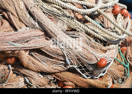 Close up sullo sfondo di un mucchio di bobine di pesca in mare net con colorate galleggianti vivaci e corde di cavo a porto Foto Stock