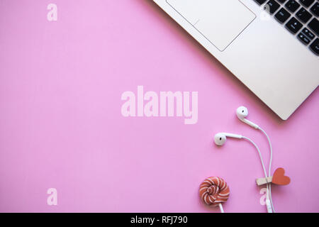 Area di lavoro in rosa colore alla moda. Laptop e le cuffie nelle vicinanze. Inizio della vacanza o la comparsa di Valentino o un altro evento di amore. Vicino a t Foto Stock