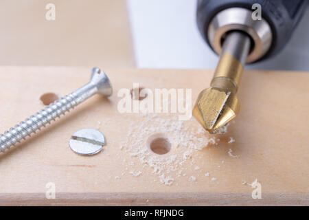 Foratura e approfondimento fori in legno. La svasatura e altri accessori per piccoli lavori di falegnameria. Sfondo chiaro. Foto Stock