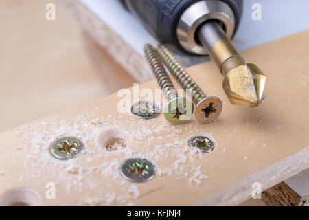 Foratura e approfondimento fori in legno. La svasatura e altri accessori per piccoli lavori di falegnameria. Sfondo chiaro. Foto Stock