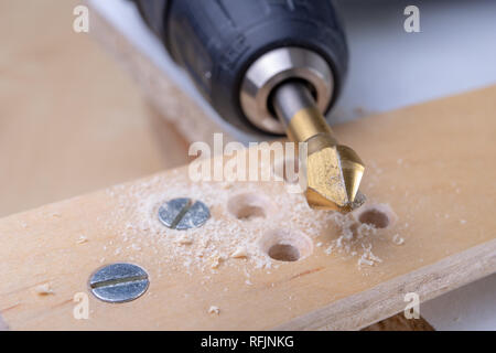 Foratura e approfondimento fori in legno. La svasatura e altri accessori per piccoli lavori di falegnameria. Sfondo chiaro. Foto Stock