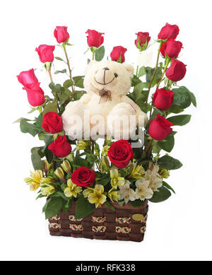 Regalo floreale disposizione realizzata con rose rosse con lunghi steli all'interno di una pentola di marrone con Teddy bear su sfondo bianco Foto Stock