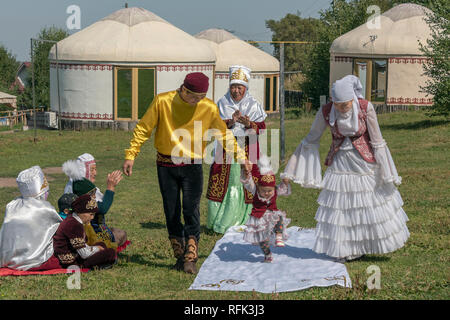 Alta stepping 'Tusau Kesu' cerimonia (taglio della corda) entusiasta bambino con la famiglia vestita a festa, Almaty, Kazakhstan Foto Stock