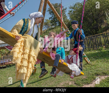 Esuberanza, giovani il kazako vestita a festa su altalena, Almaty, Kazakhstan Foto Stock