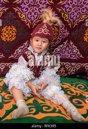 Giovane ragazza kazaka in abbigliamento traditioanal seduta in una yurt, Almaty, Kazakhstan Foto Stock