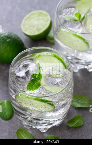 Due bicchieri di cocktail con calce su sfondo di ardesia Foto Stock