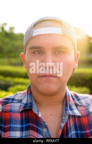Giovane uomo asiatico che indossa il tappo durante i momenti di relax presso il parco in Bangko Foto Stock