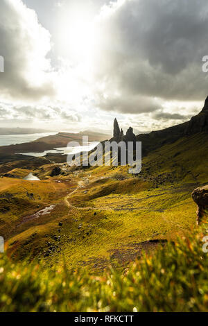 Il vecchio uomo di Storr con erba in primo piano e il sole lo scoppio attraverso la drammatica nuvole durante l'autunno (Isola di Skye in Scozia, Regno Unito) Foto Stock