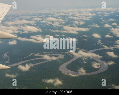 Vista dalla finestra di aereo. Ala di un aeroplano che vola sopra le nuvole oltre il fiume del Amazon. Vista superiore della foresta pluviale amazzonica. Il Perù, Brasile. La Colombia. Foto Stock