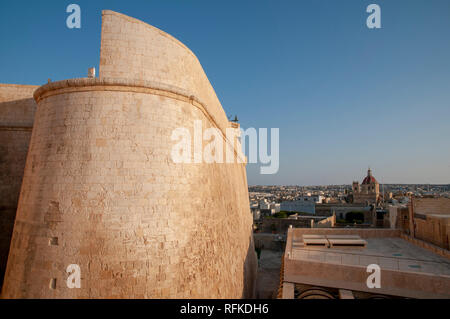 La Cittadella con la parete curva di St Michael bastione e Basilica di San Giorgio sopra i tetti di Victoria, capitale dell'isola di Gozo, Malta. Foto Stock