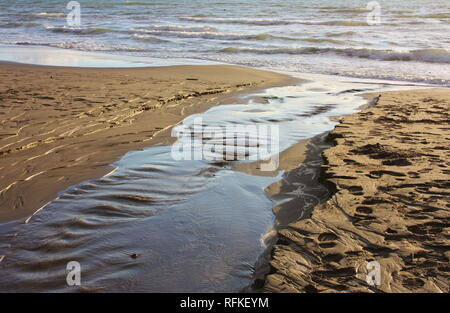 Flusso di acqua o di perdita di acqua sulla spiaggia di sabbia di mare. torrent o stream. pozza o stagno Foto Stock